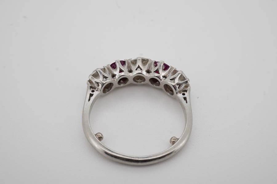 A ruby and diamond five-stone ring, set with an alternating sequence of antique cushion-shaped diamonds totalling approximately 1.50 carats, spaced with circular-cut rubies, mounted in platinum, size M (sizing beads), Br